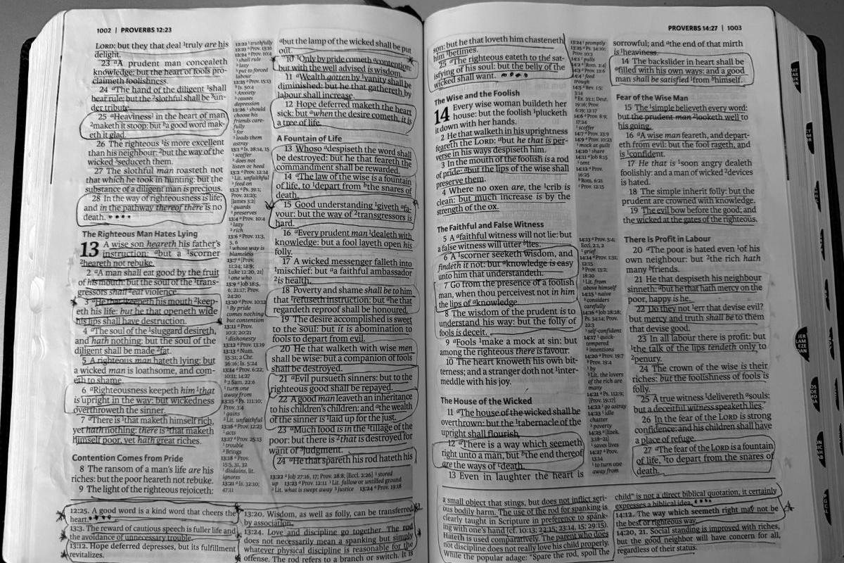 An open Bible at Proverbs 13, marked up in pen